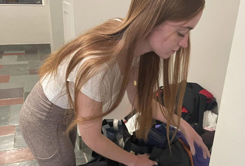 A female student sorts through items in a donation bin